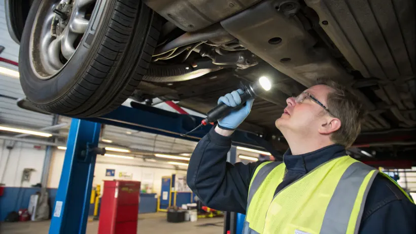 RDW inspecteur die de onderkant van een geïmporteerde auto controleert tijdens een technische keuring